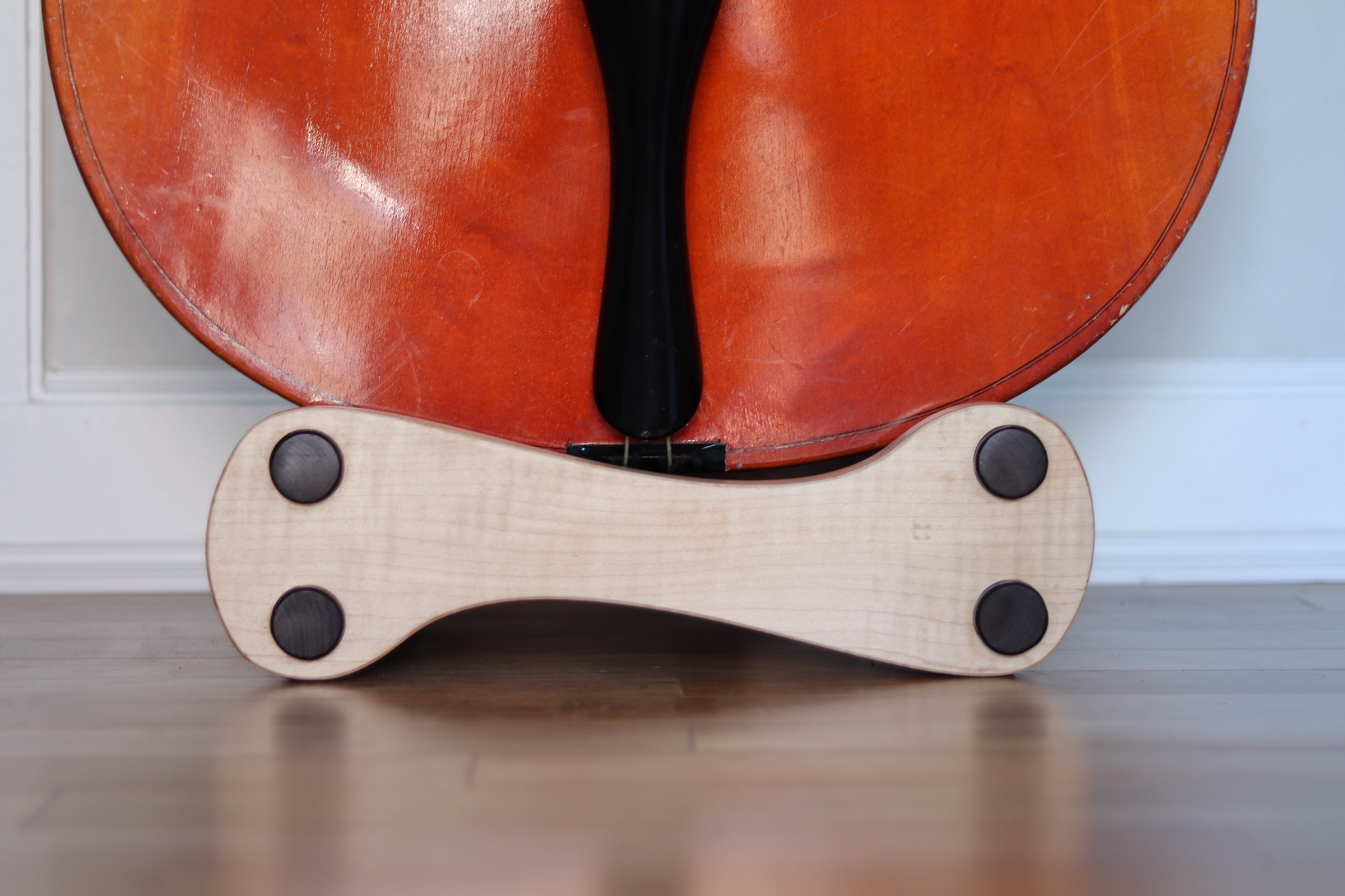 The finished bass stand in maple and walnut — dramatic lighting showing organic curves and precision dowel joinery