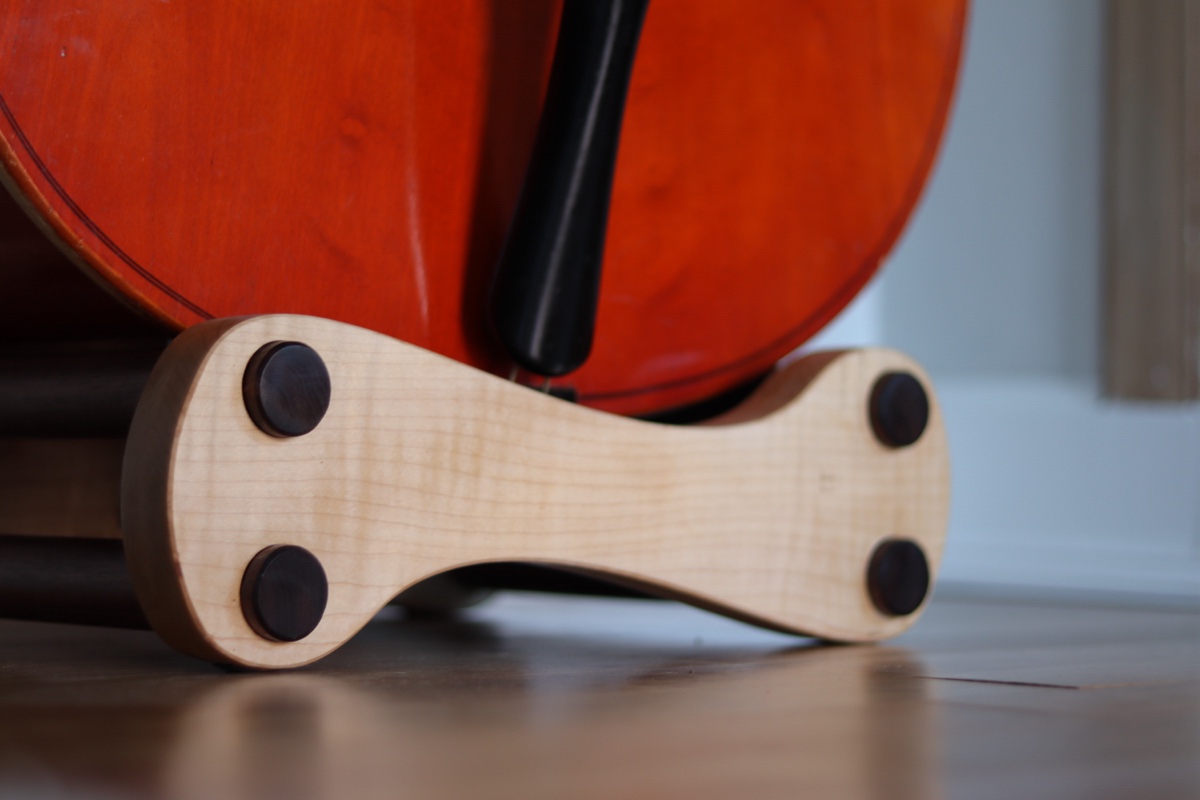Close-up detail — curly maple figure and walnut dowels, warm light catching the grain