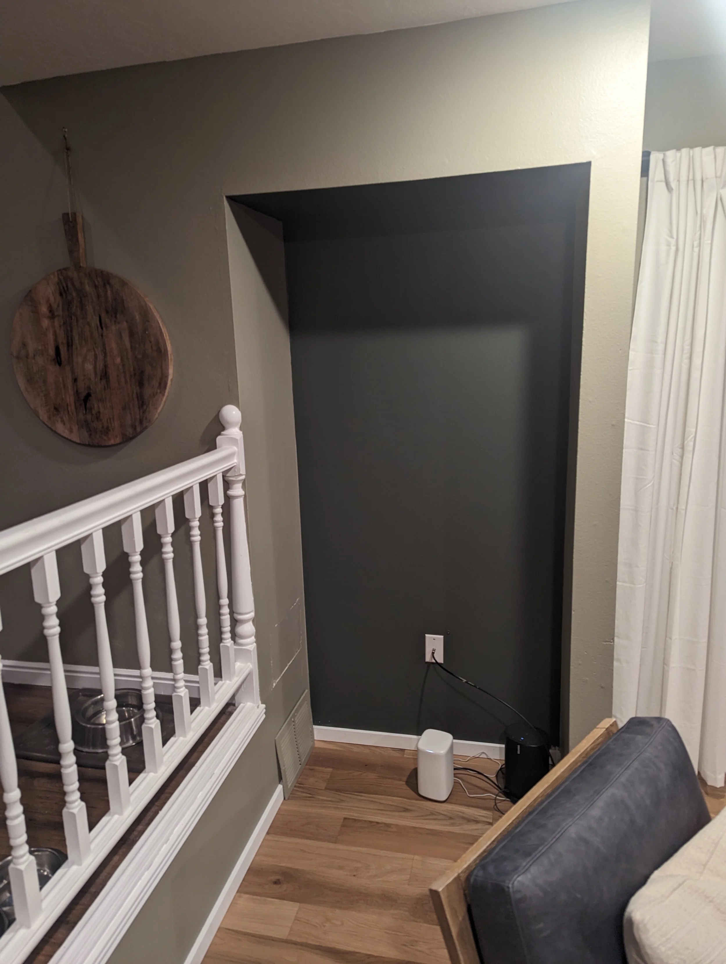Empty nook in Jill's family room before shelves — dark painted wall, staircase railing