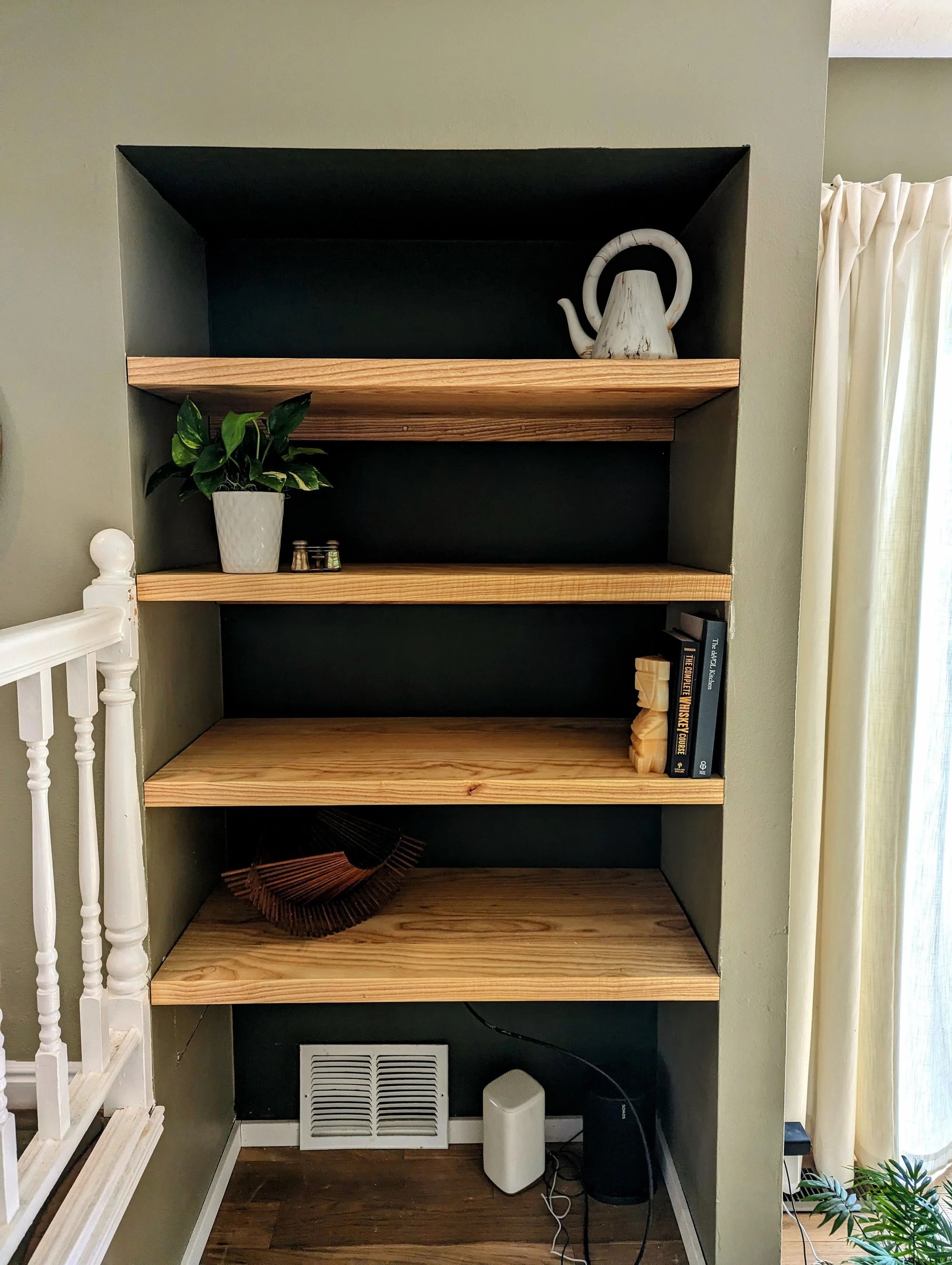 Finished shelves styled with plants, books, sculpture, and decorative objects
