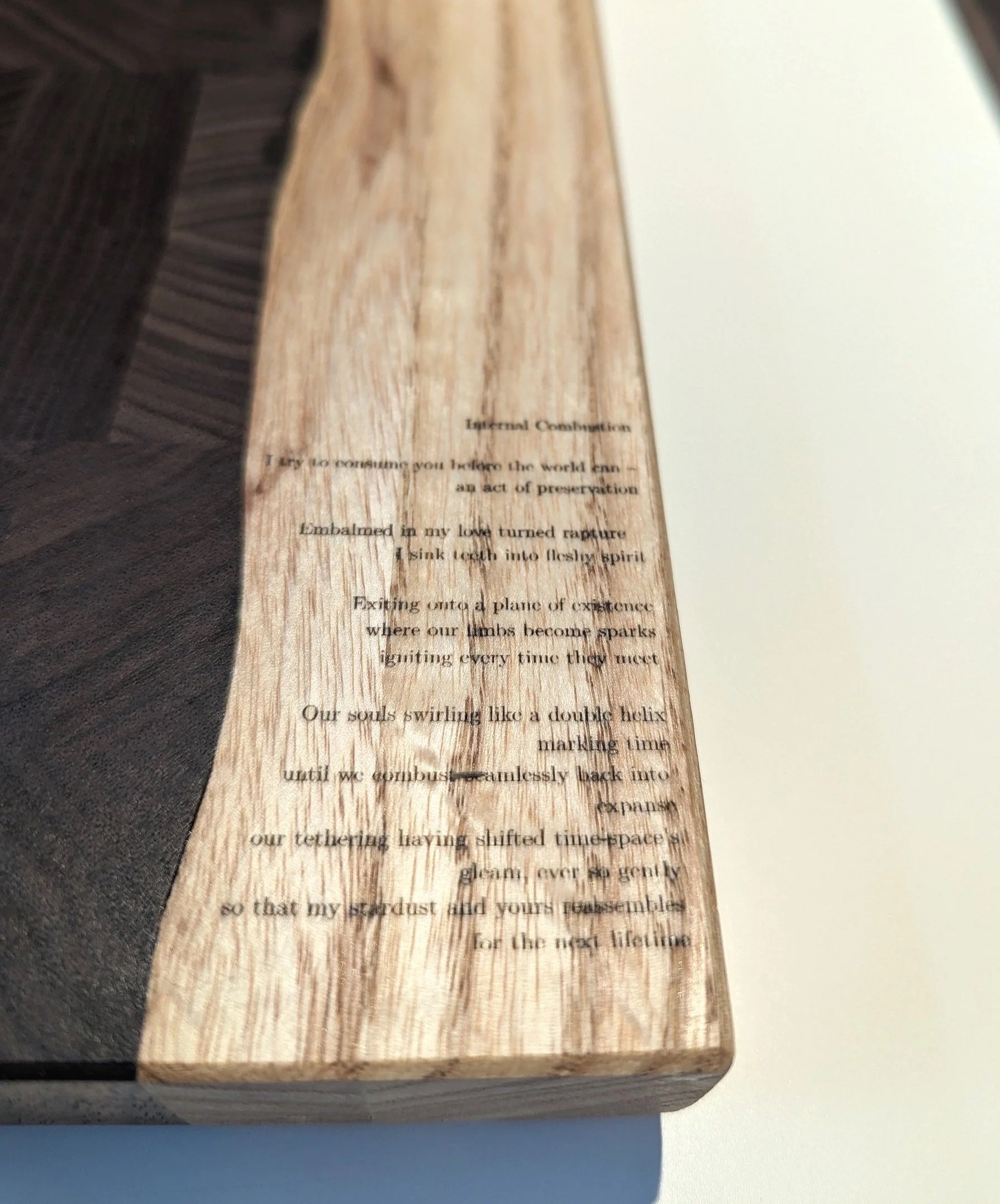 Close-up of Chandani's poem 'Internal Combustion' laser-etched into live-edge oak