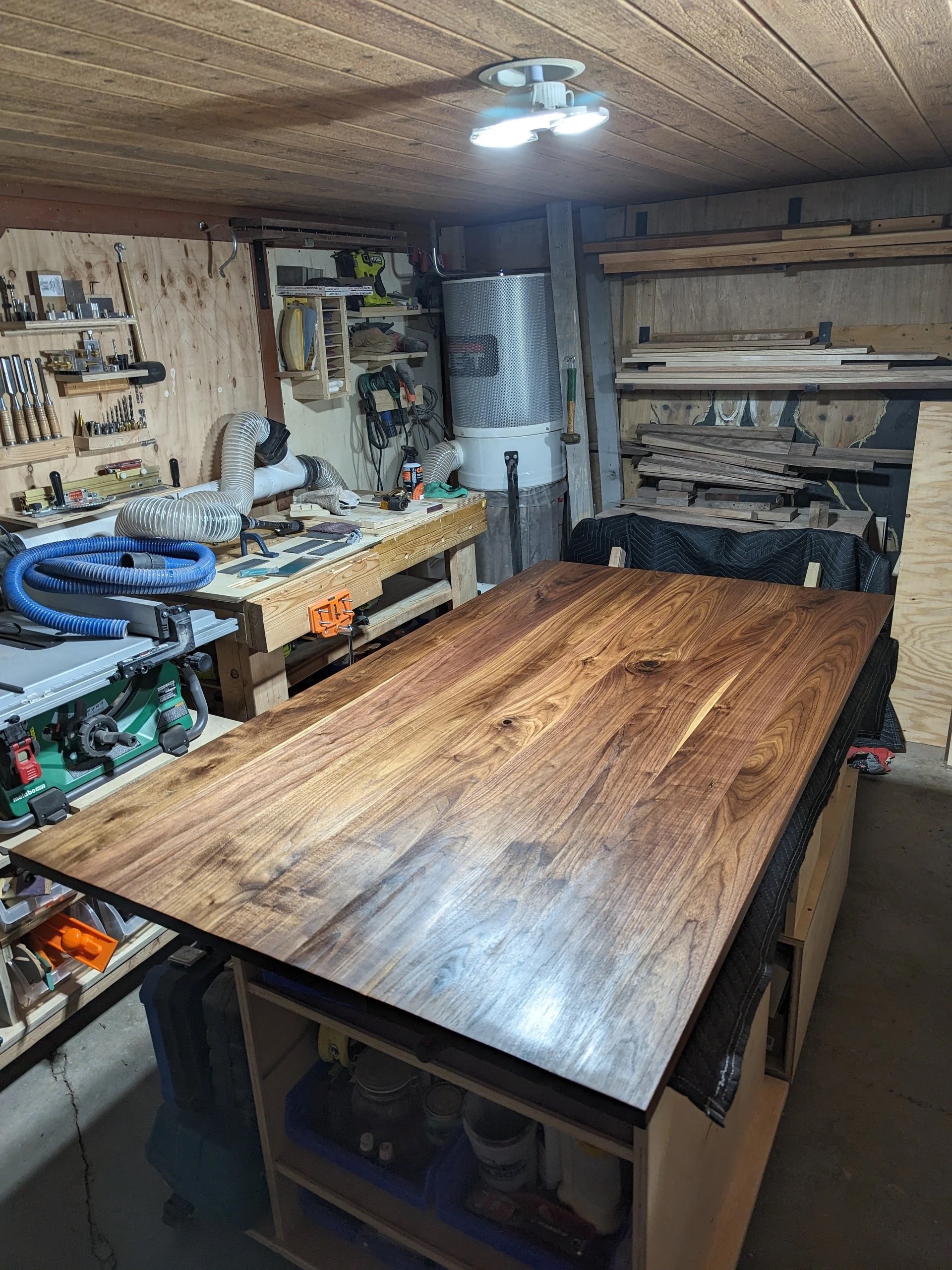 Finished walnut tabletop in the workshop, oiled and waxed — the grain at full depth