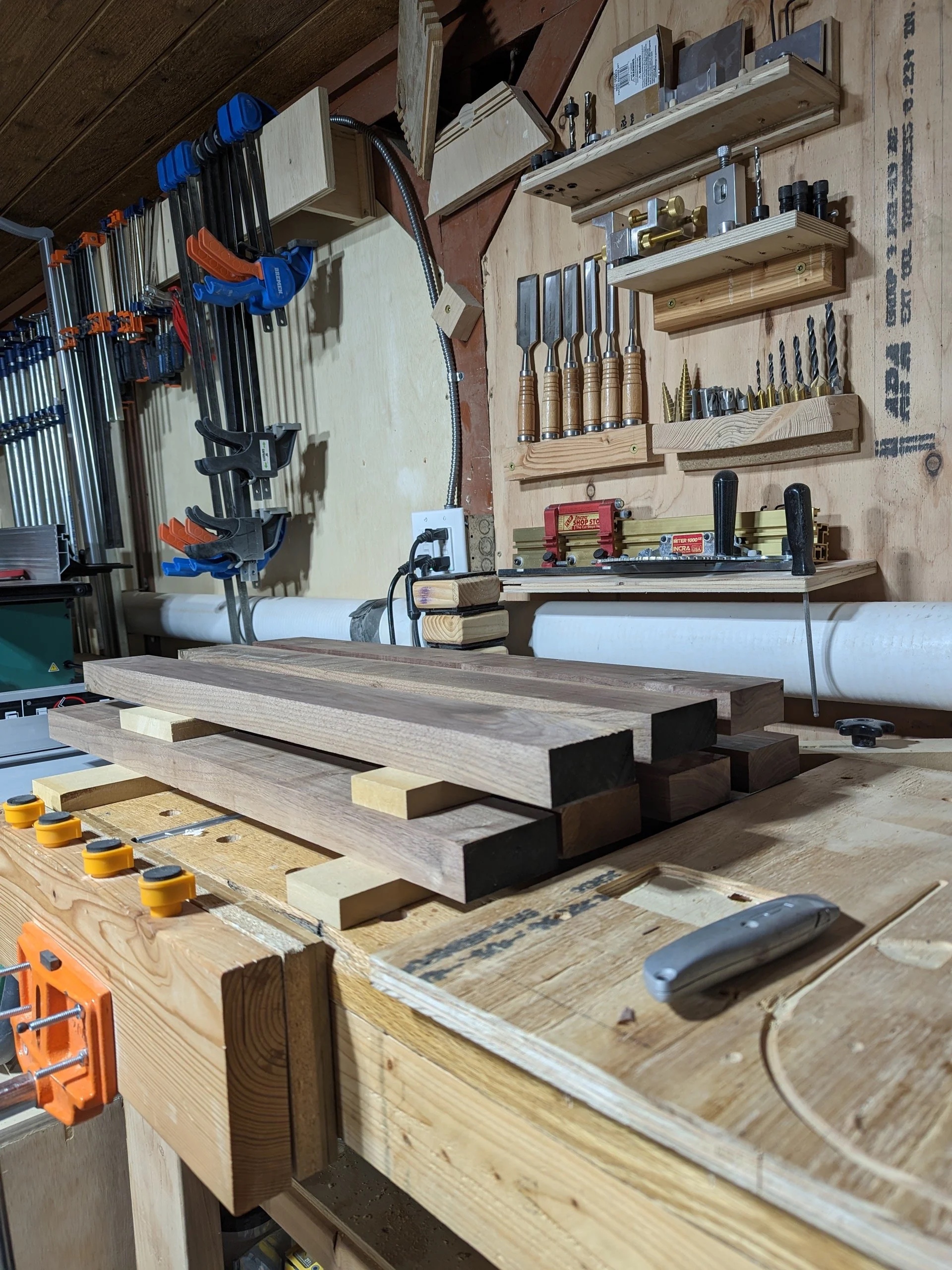 Milled walnut boards stacked on the workbench, planed to thickness