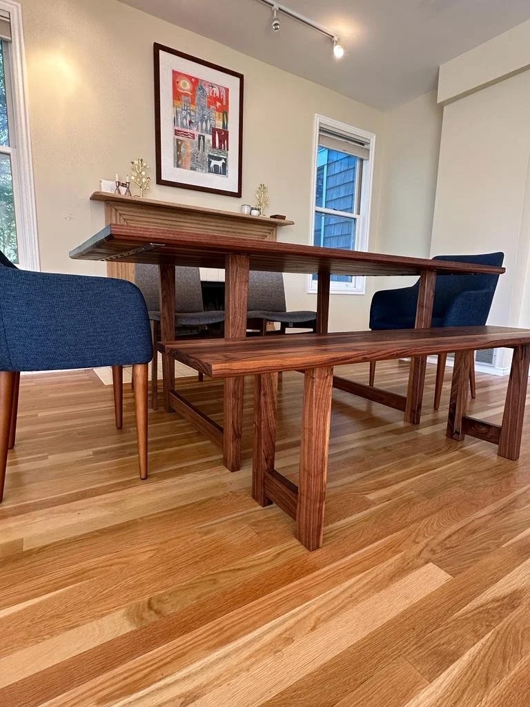 The table and bench from the side, showing the leg structure and natural walnut grain