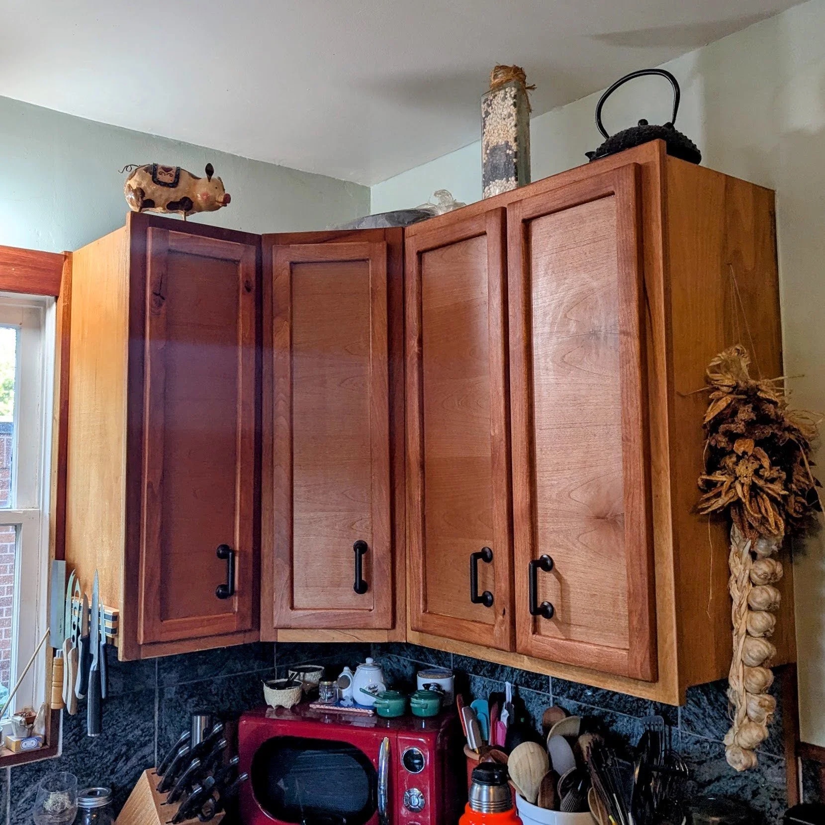 Cherry upper cabinet doors with cast iron handles — corner view of finished kitchen
