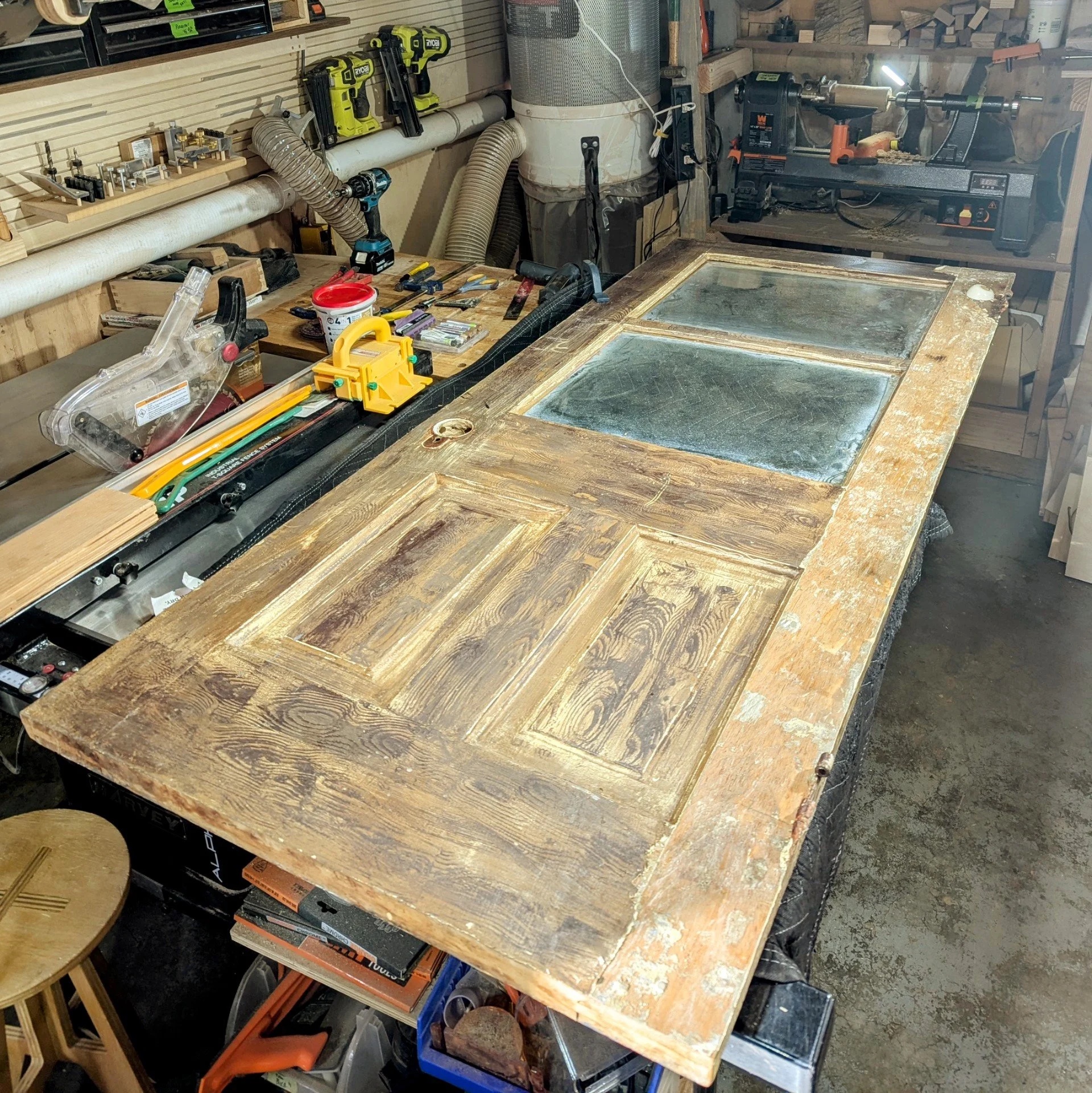 Old pine door on workbench — sixty years of paint being stripped away