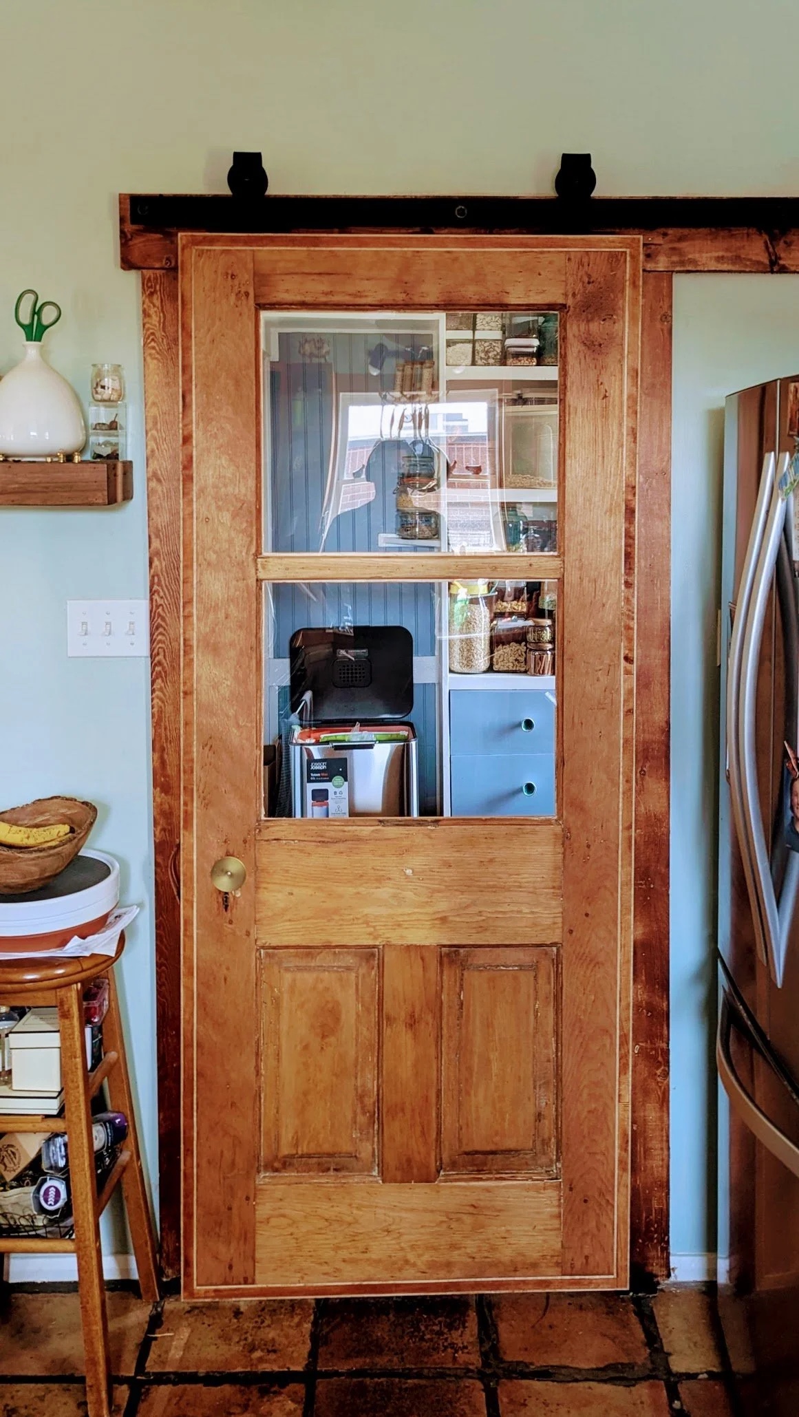 Restored pine barn door installed in kitchen — maple frame, glass panels, barn door hardware