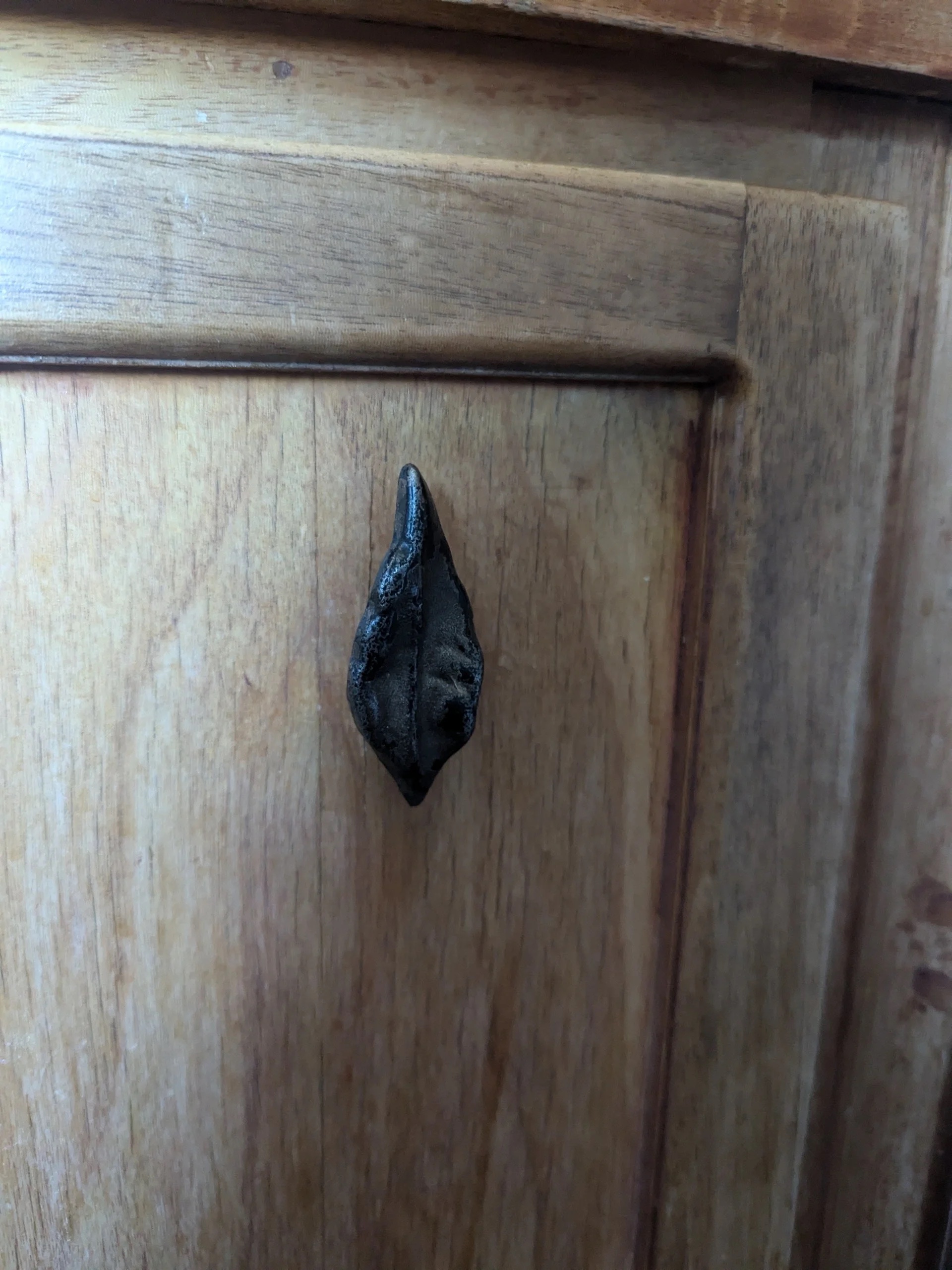 Cast iron leaf handle on cherry cabinet door