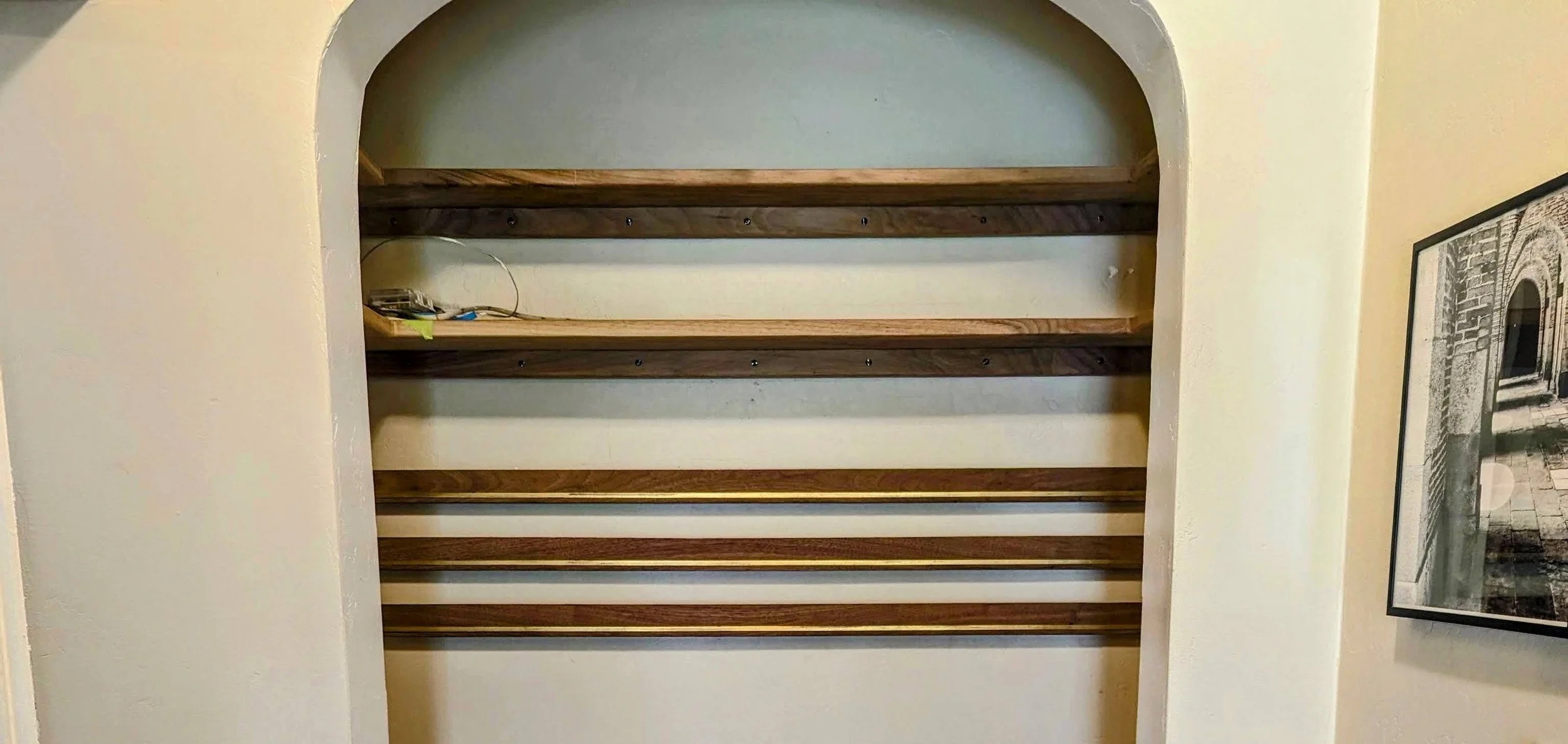 French cleats installed in the nook — walnut rails with brass inlay strips