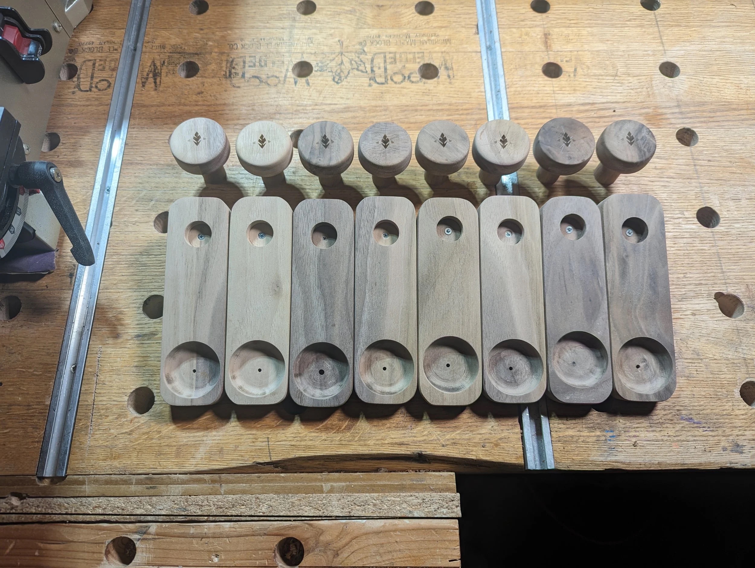 French cleat hangers — walnut with brass knobs, lined up on the workbench