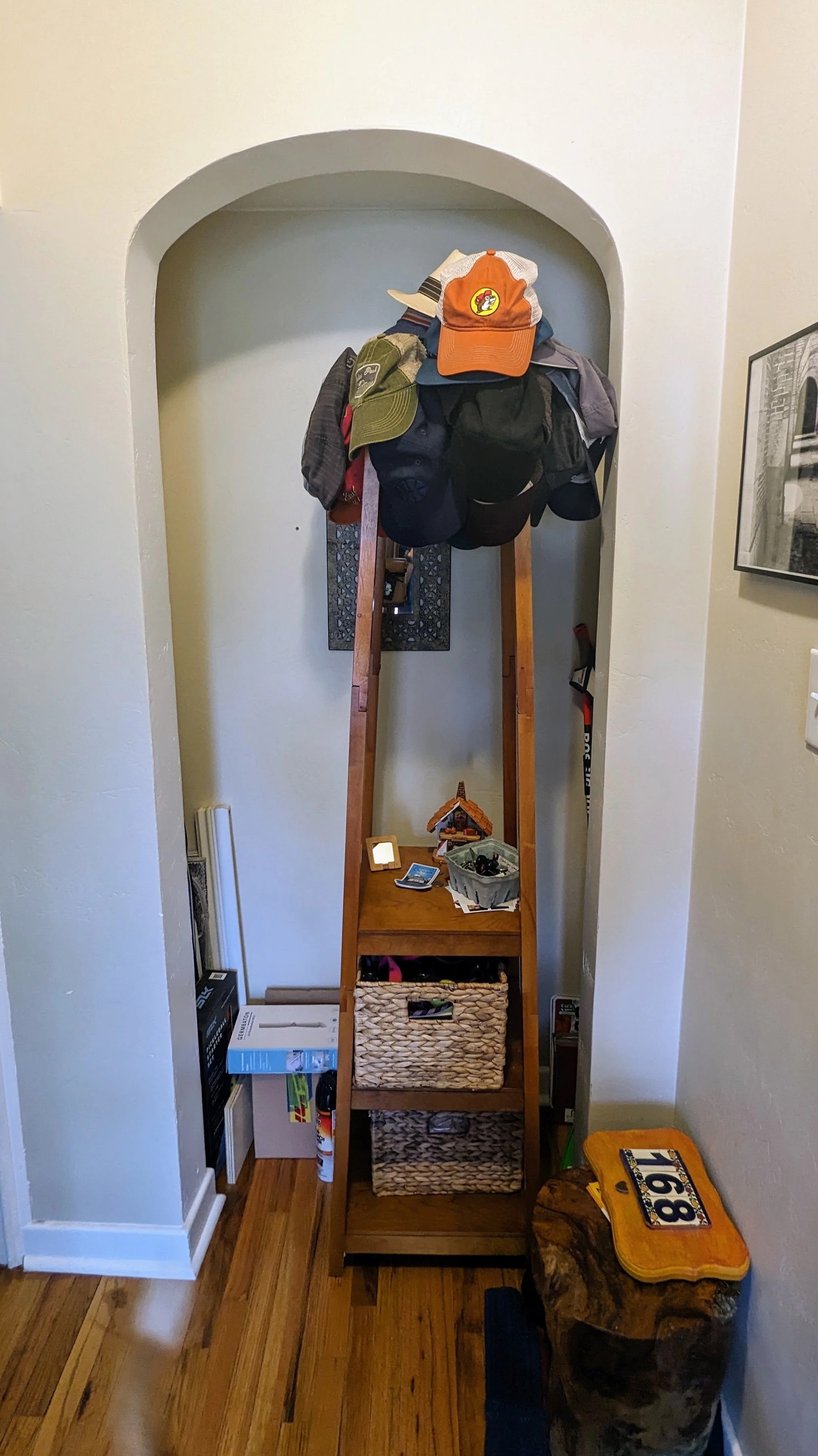 The nook before — cluttered arched alcove with a makeshift coat rack