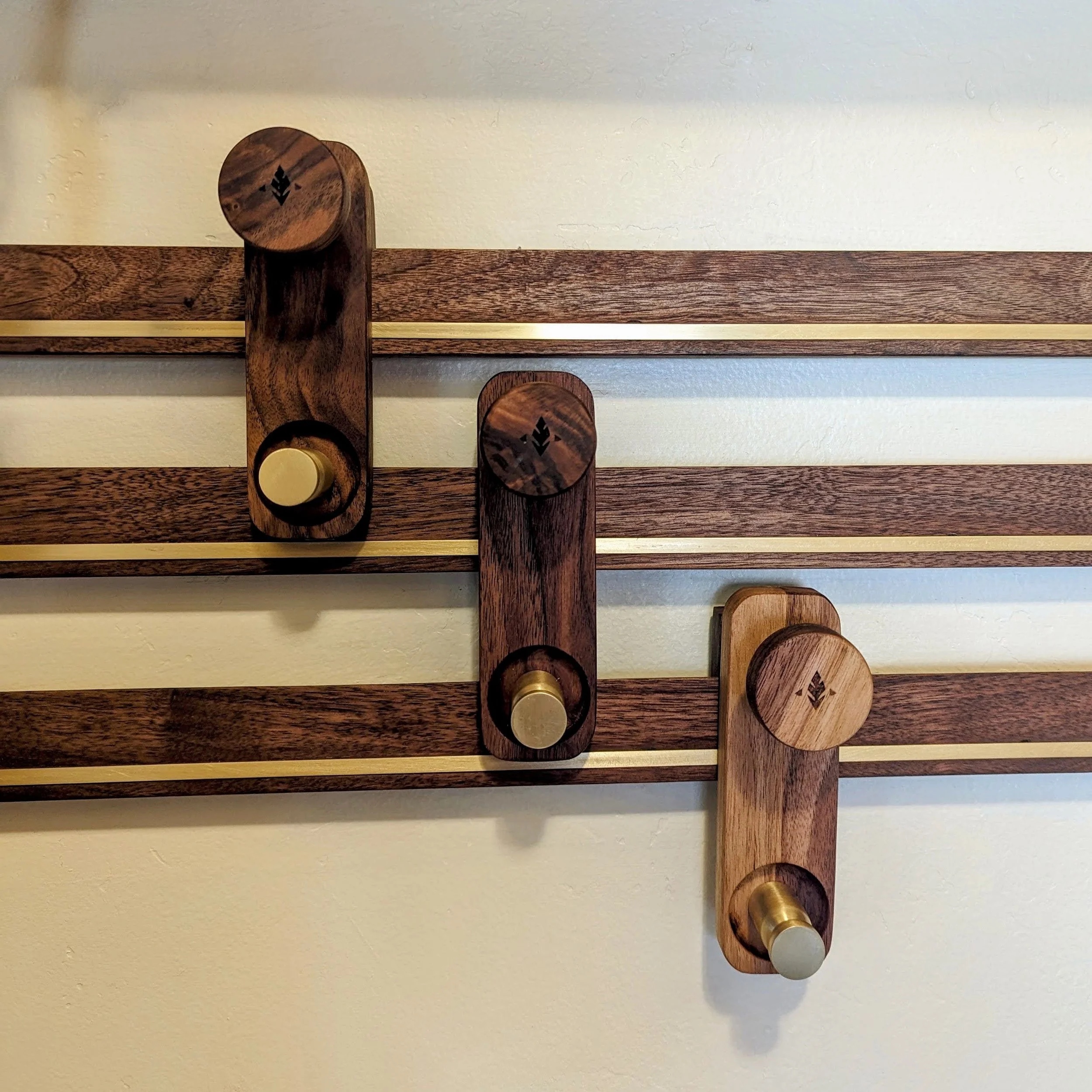 French cleat hangers installed — walnut with brass strips and two-size brass knobs