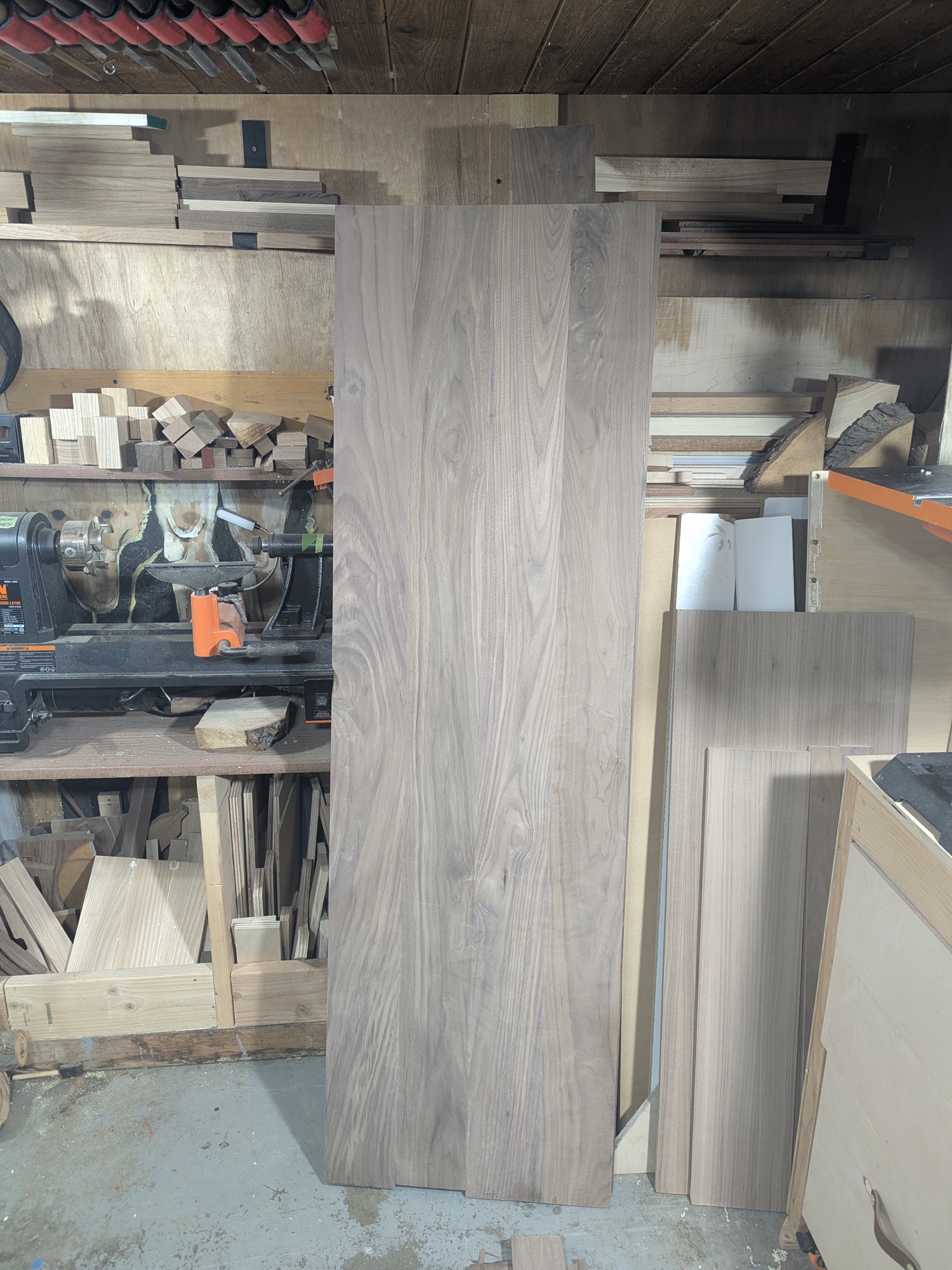 Finished walnut panels standing in the shop — grain flowing through the glue joints