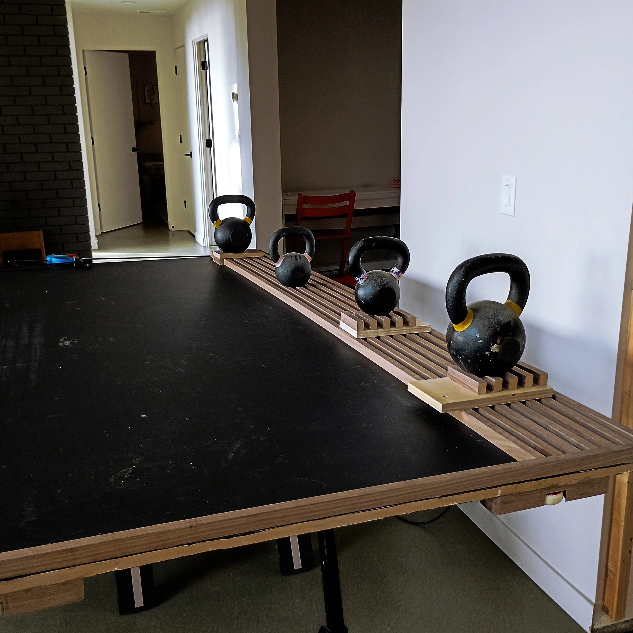 Walnut slats being glued to MDF panel with kettlebells as clamps