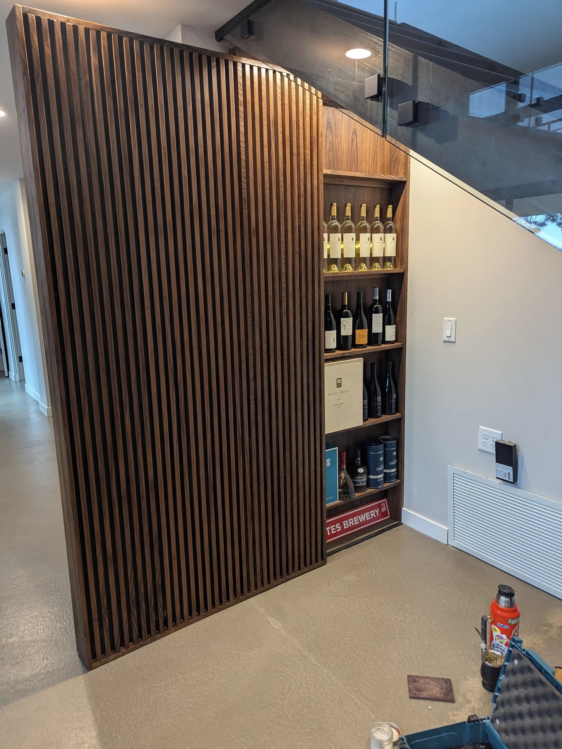 The Nook — finished slatted walnut door slid open, wine closet visible with bottles on walnut shelves