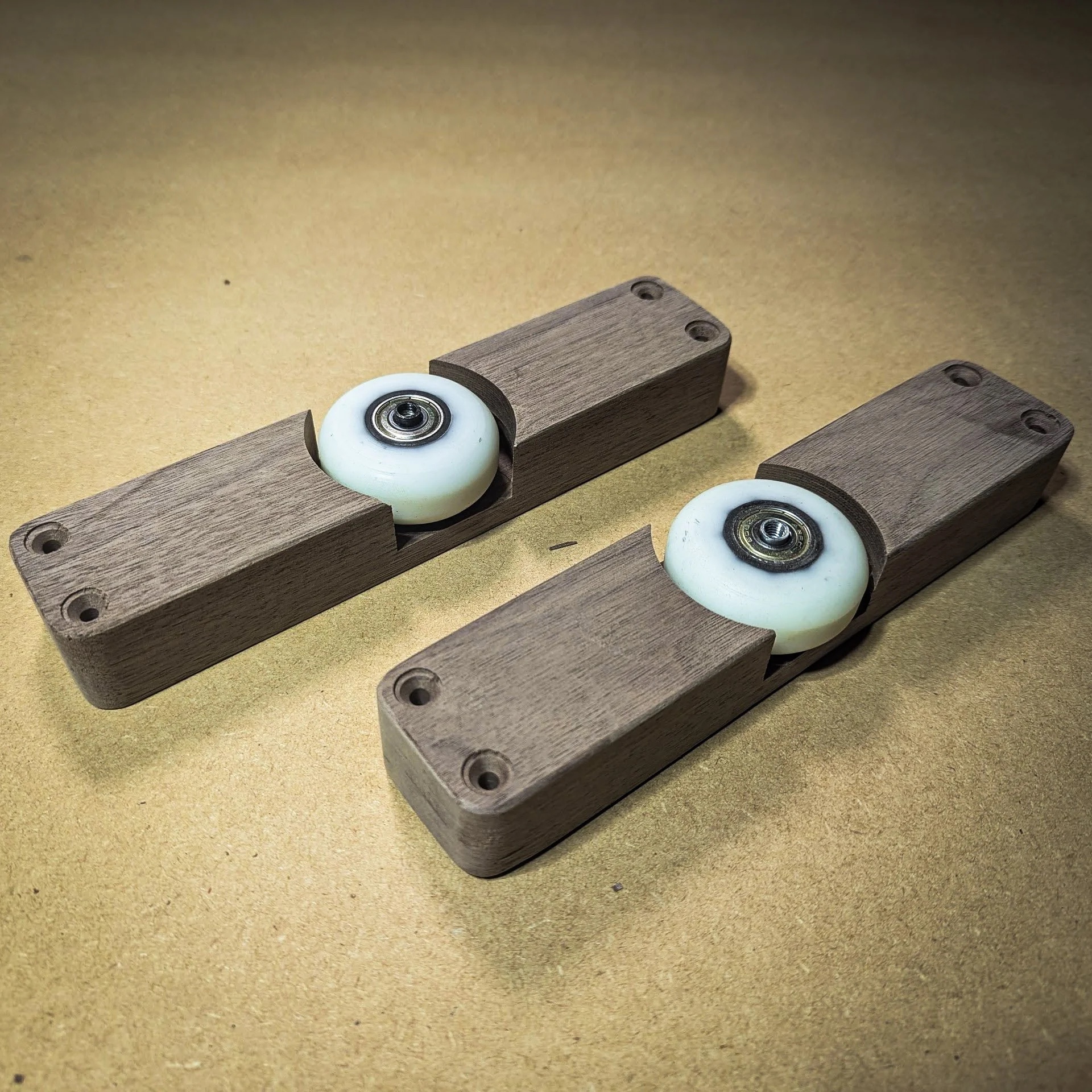 Custom walnut wheel mounts with inline skate bearings for the 200-pound sliding door