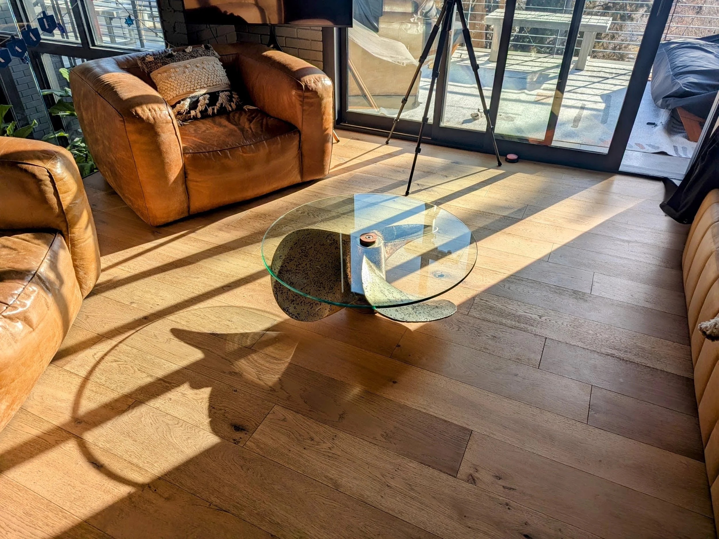 La Propela table from a lower angle, showing the glass top and leather furniture
