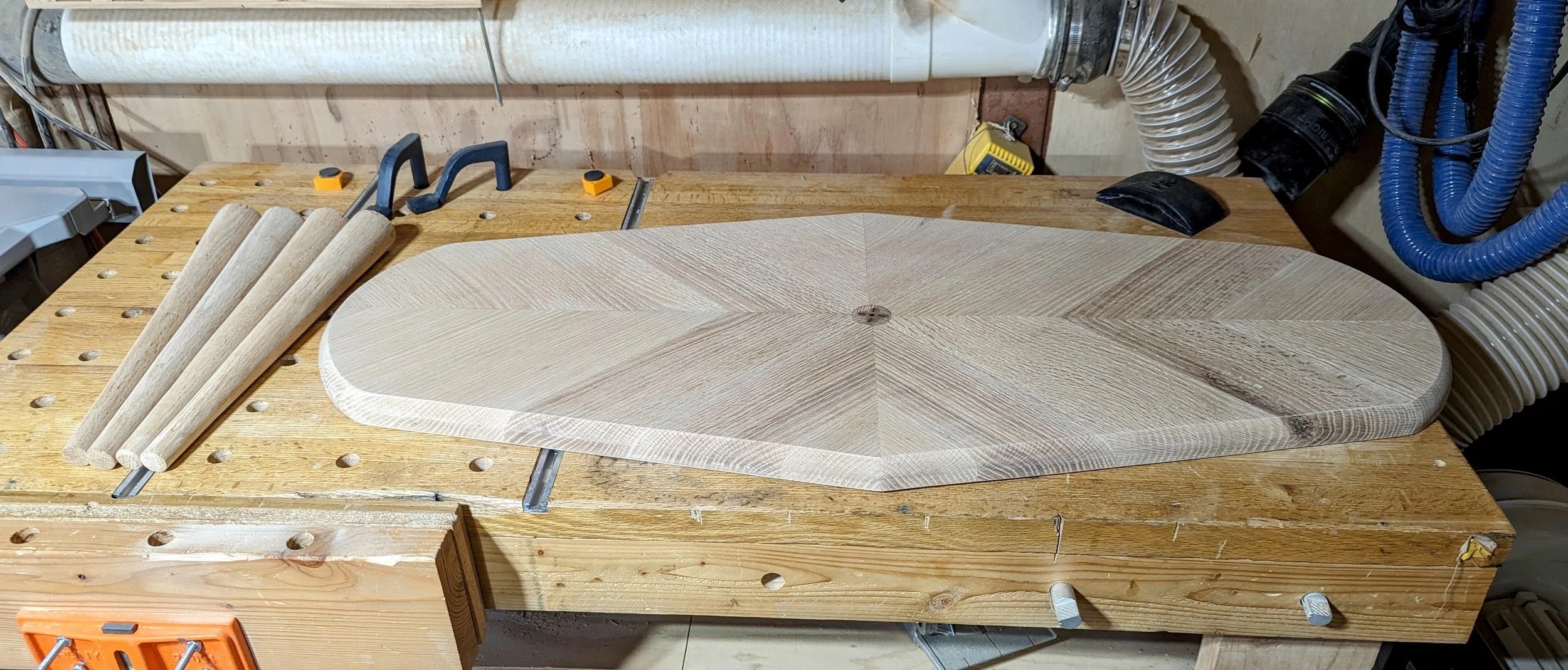All five parts on the workbench — tabletop with chevron pattern and four turned legs