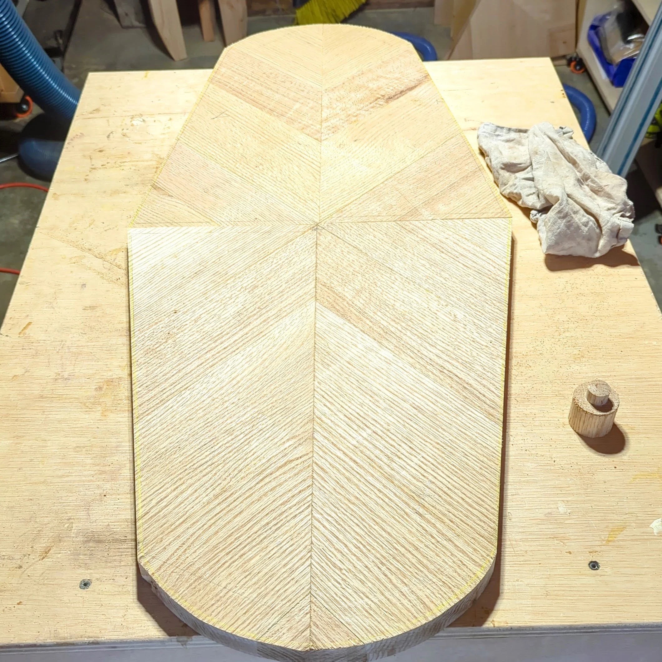 The tabletop cut to its diamond-rounded shape — chevron pattern visible in raw oak