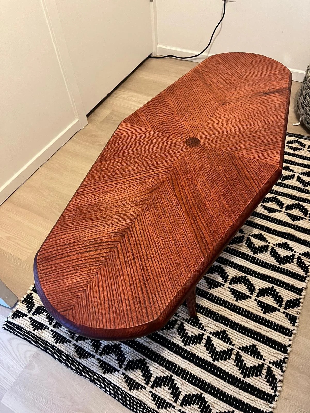The finished table from above on a patterned rug — tiger grain catching the light