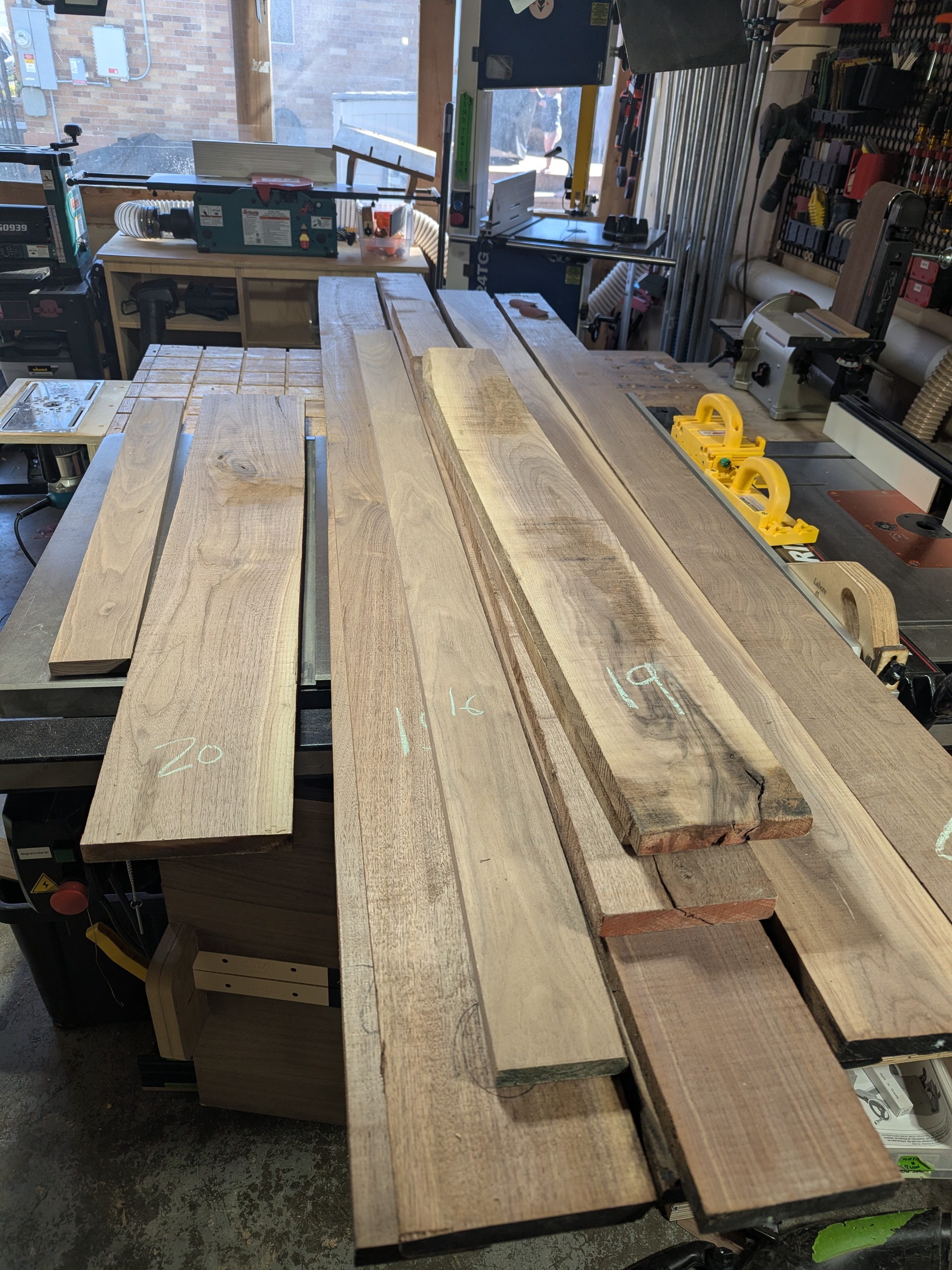 The rough cuts — 20 boards of walnut staged for crosscut, chalk marks and bark edges still visible