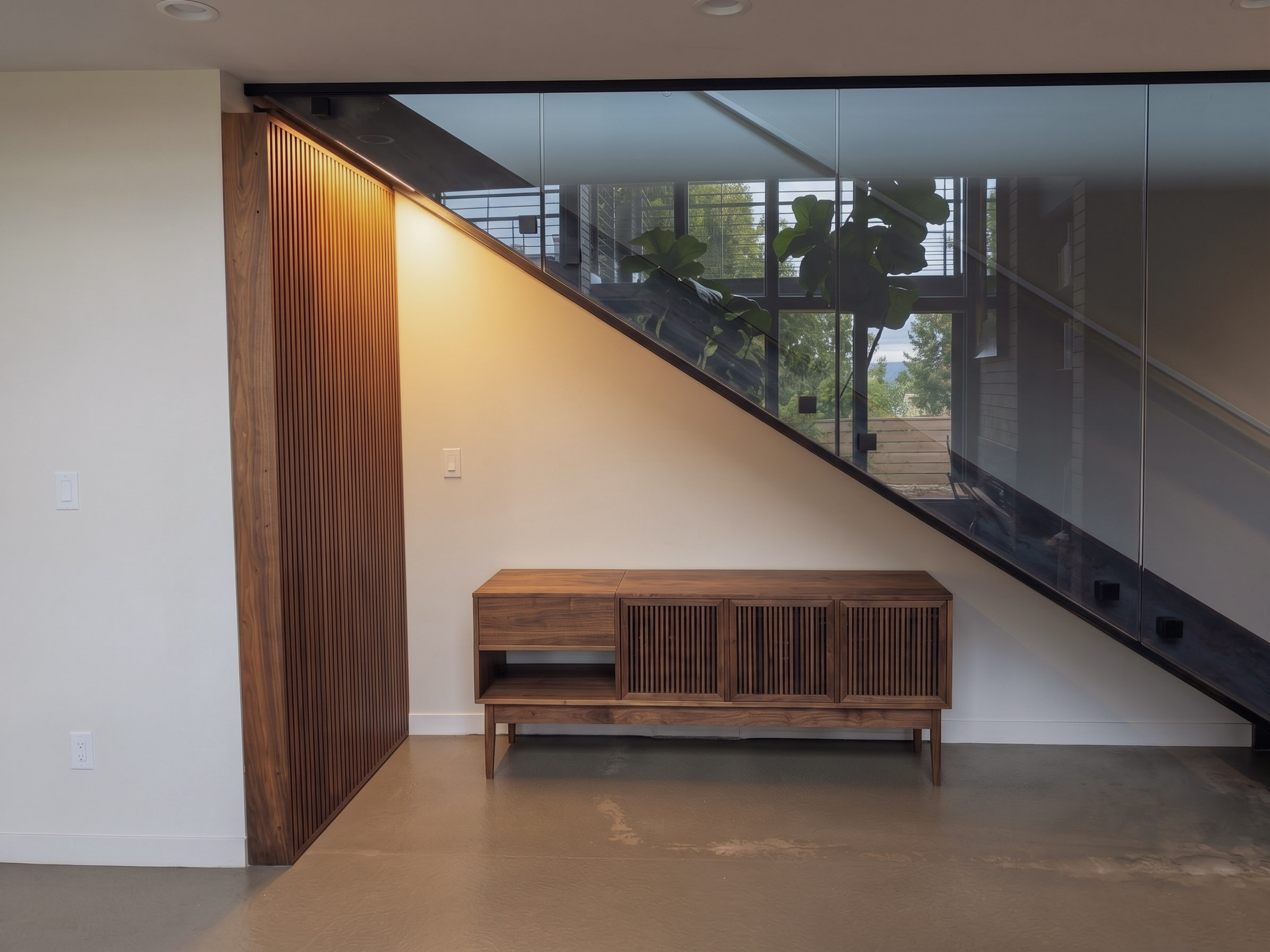 Las Patas — walnut record credenza delivered under the staircase beside The Nook's slatted wall, Salt Lake City