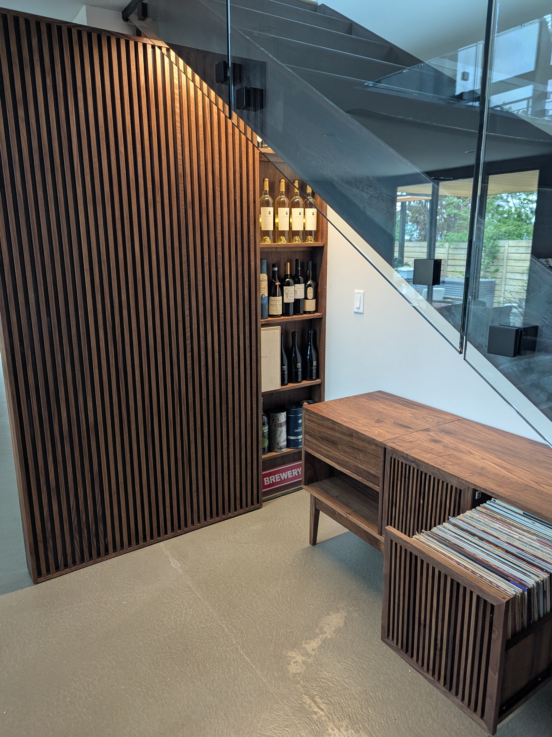 The Nook's wine closet open behind the slatted door AND Las Patas' record drawer pulled open — both pieces doing what they were built for, at once