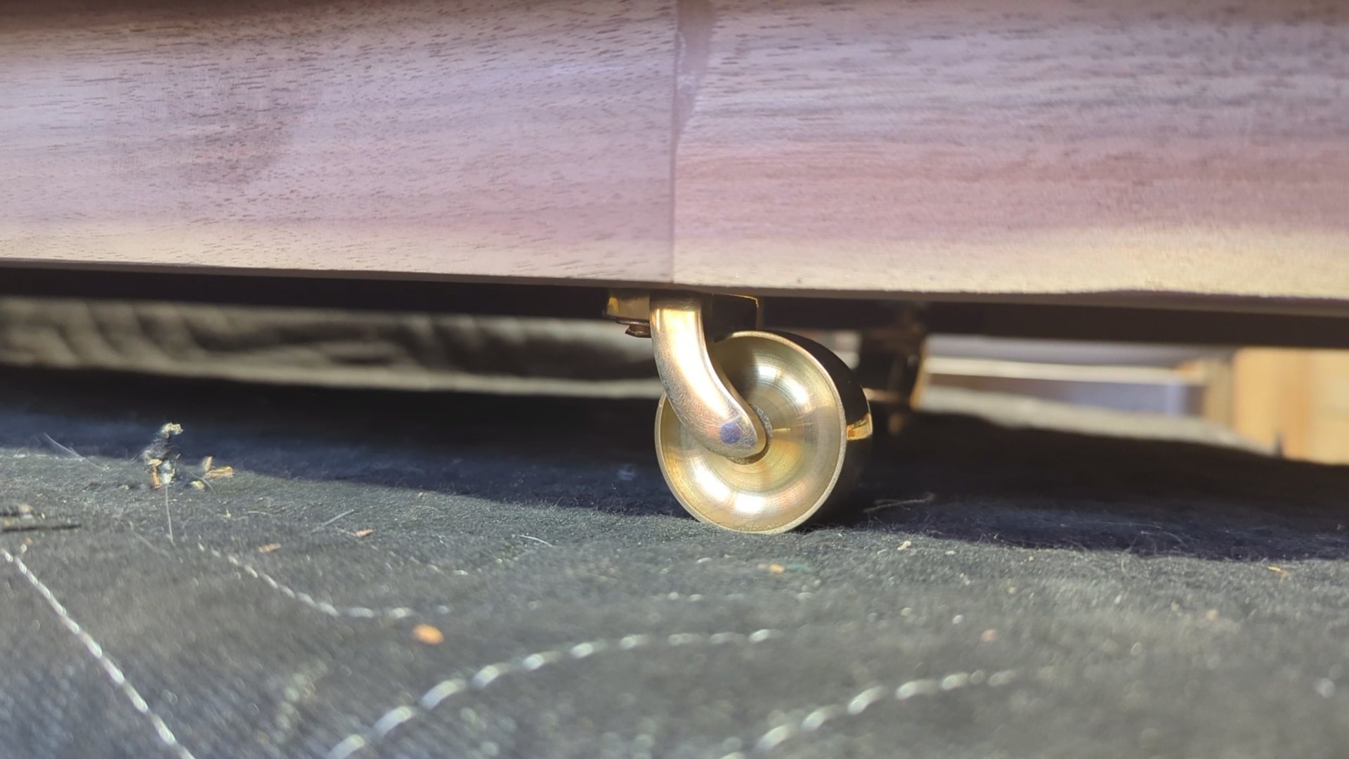 One of the brass casters tucked under the walnut base