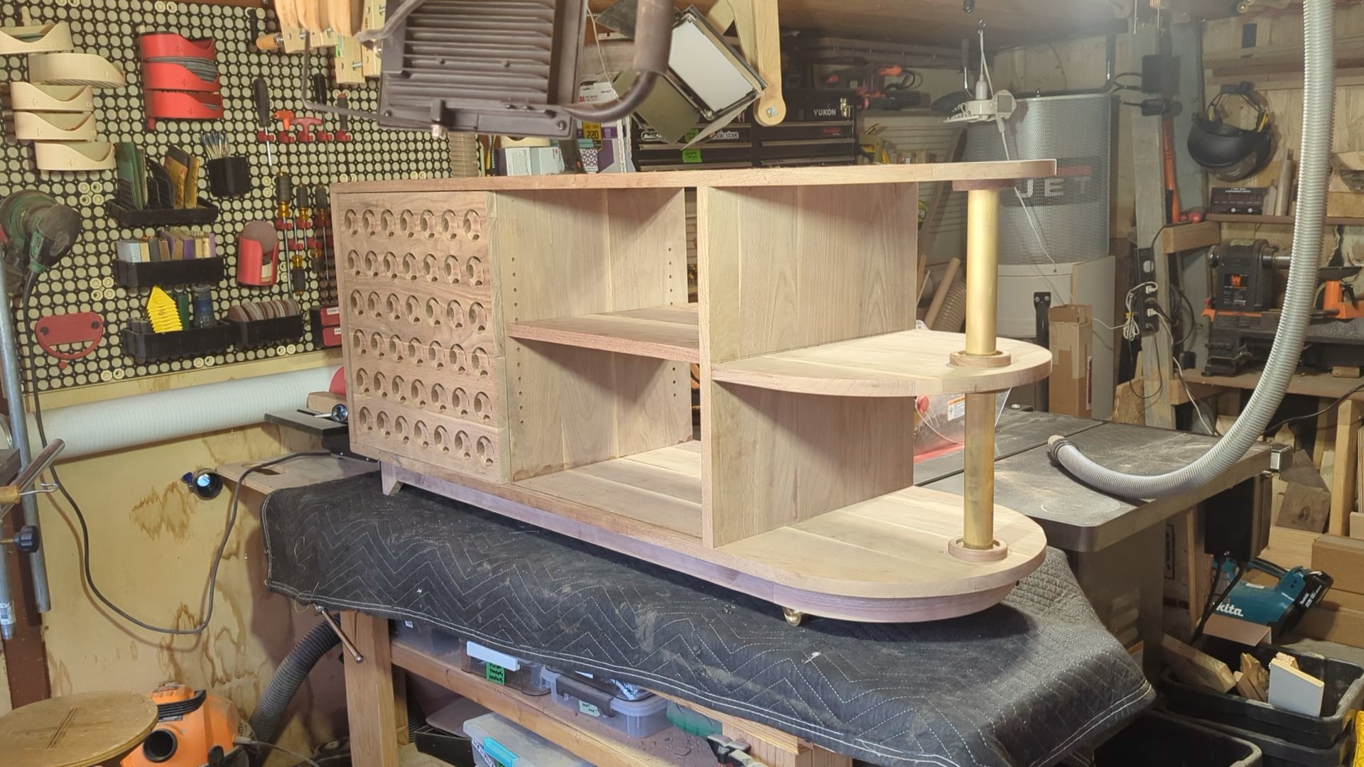 Dry fit on the bench: walnut carcass, speaker-grille door, rounded shelf end and the brass posts standing