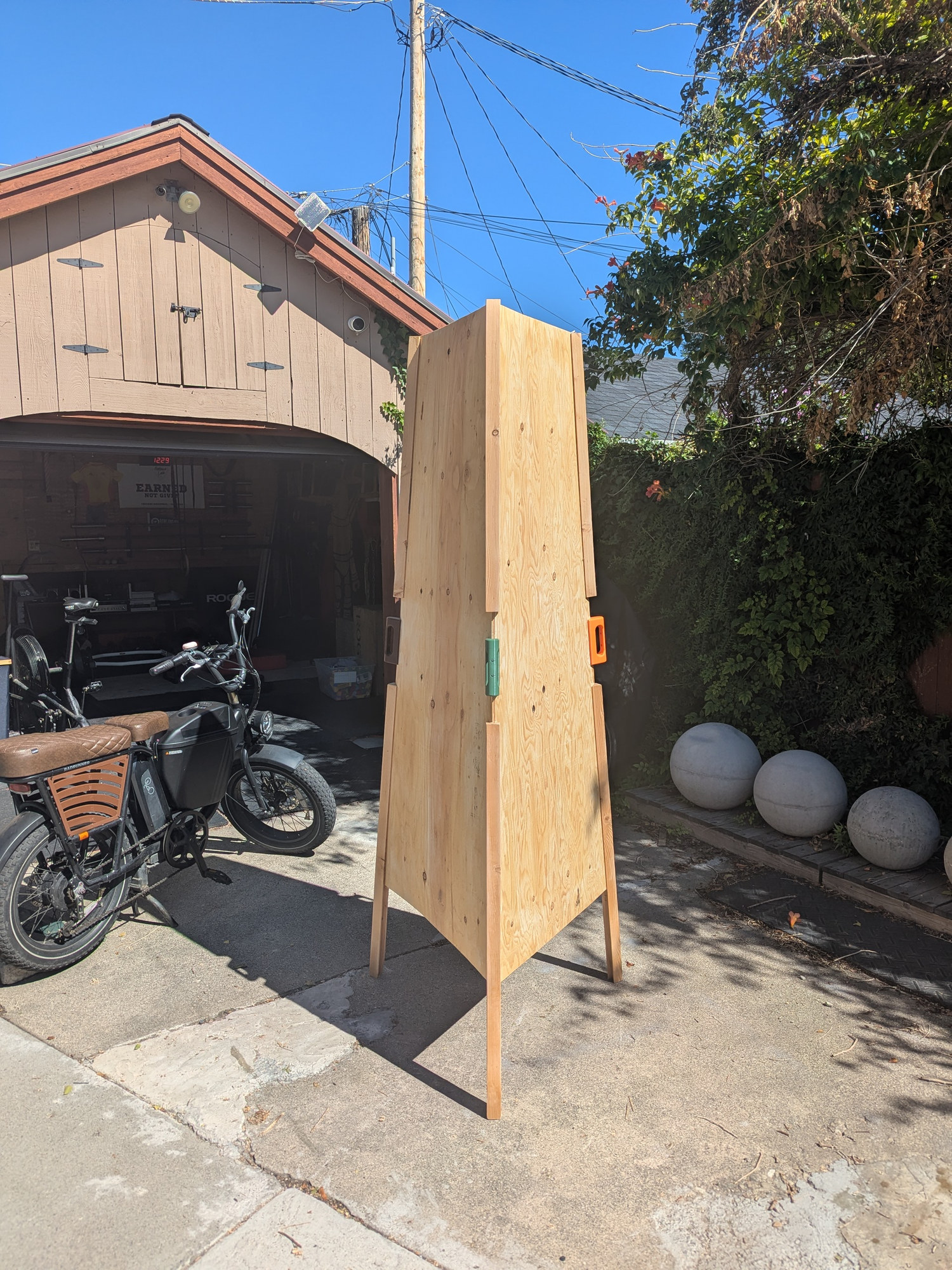 The full-size kaleidoscope standing on its three legs in the driveway, the garage behind it