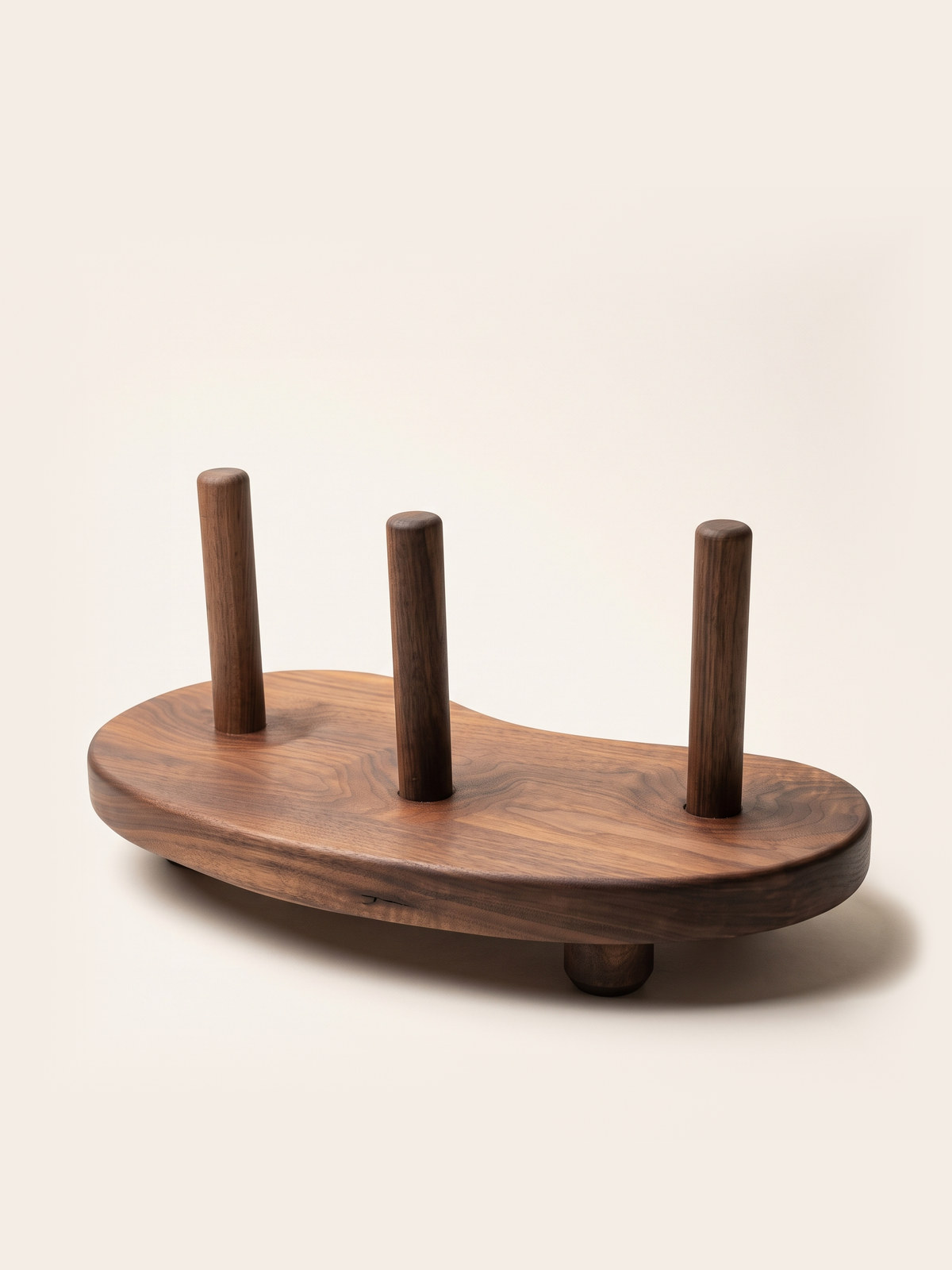 Yidaki: the finished walnut didgeridoo stand, three turned pegs on a bean-shaped slab